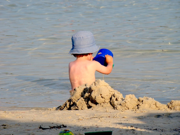niño en la playa con gorro